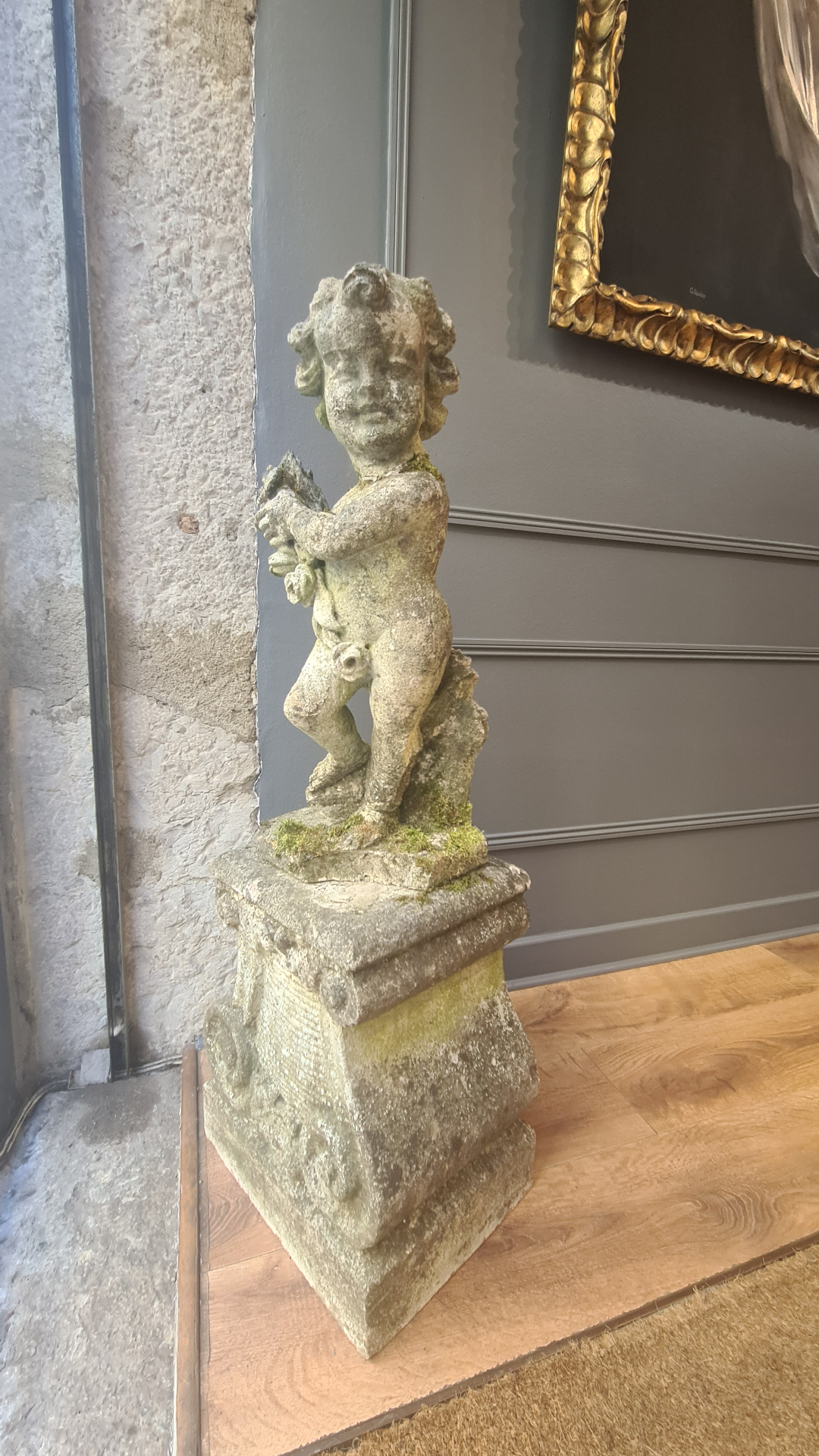 Sculpture d'angelot en pierre sur socle, dans la galerie